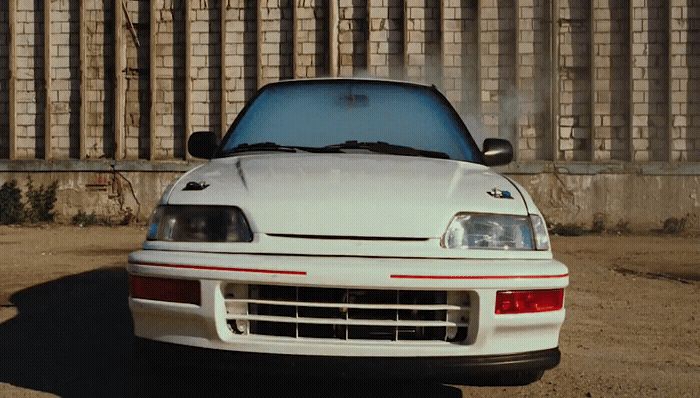 a white car parked in front of a fence