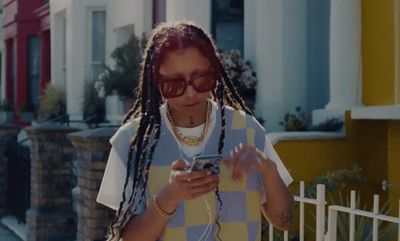 a woman with dreadlocks is looking at her cell phone