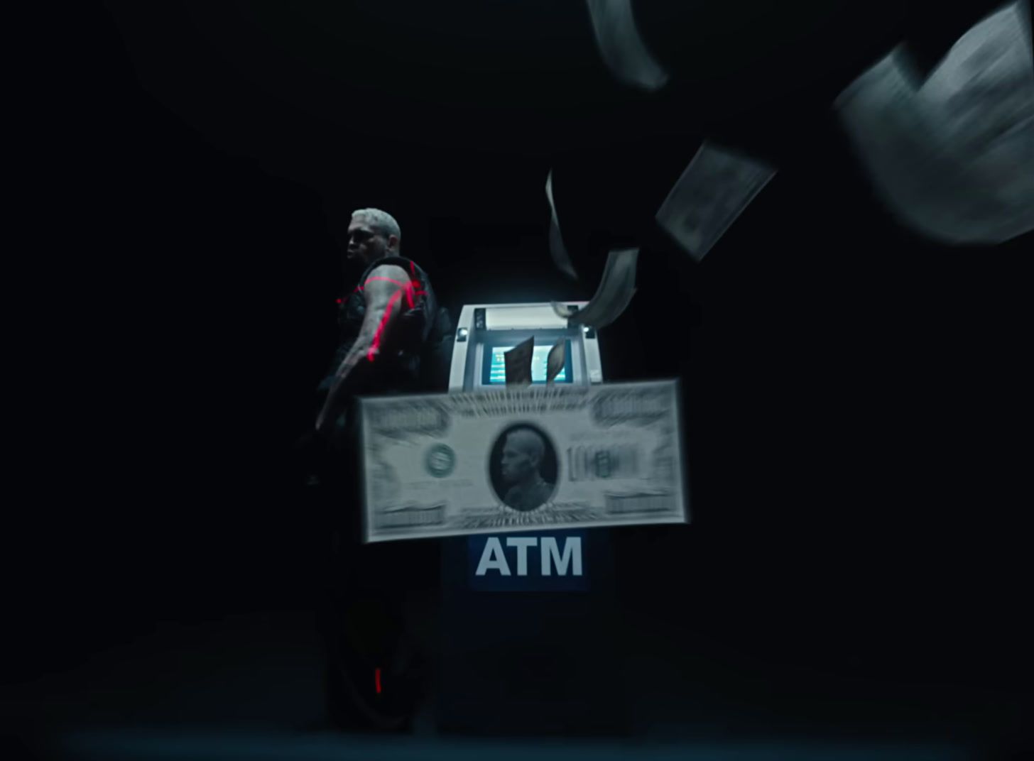 a man standing in front of a box with a dollar bill in it