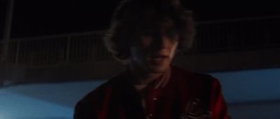 a man in a red shirt standing in the dark