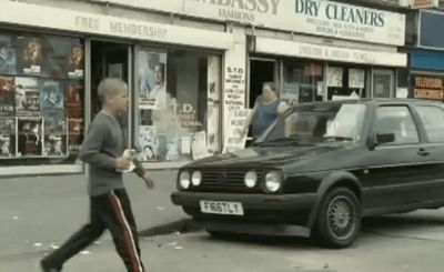 a man walking across a street next to a car