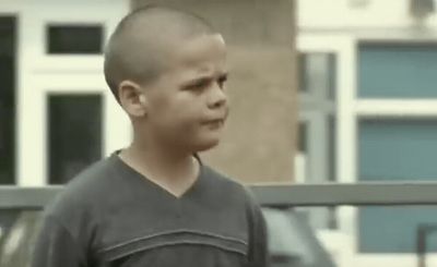 a young boy standing in front of a building