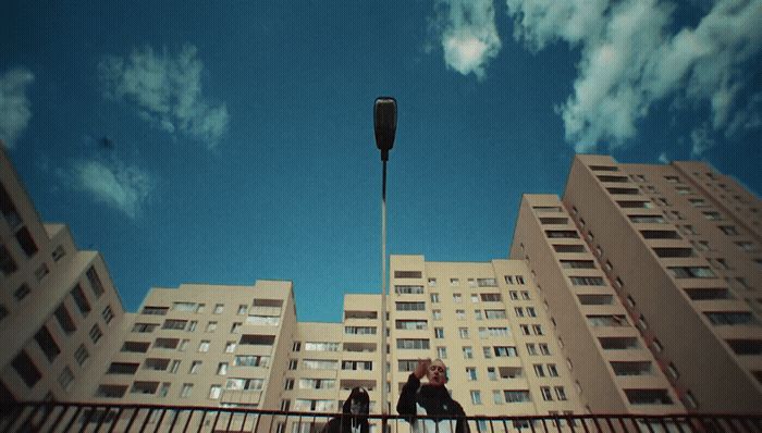 a couple of people standing on a bridge next to tall buildings