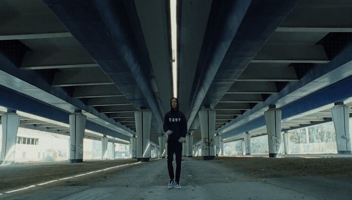 a man standing in a parking garage under a bridge