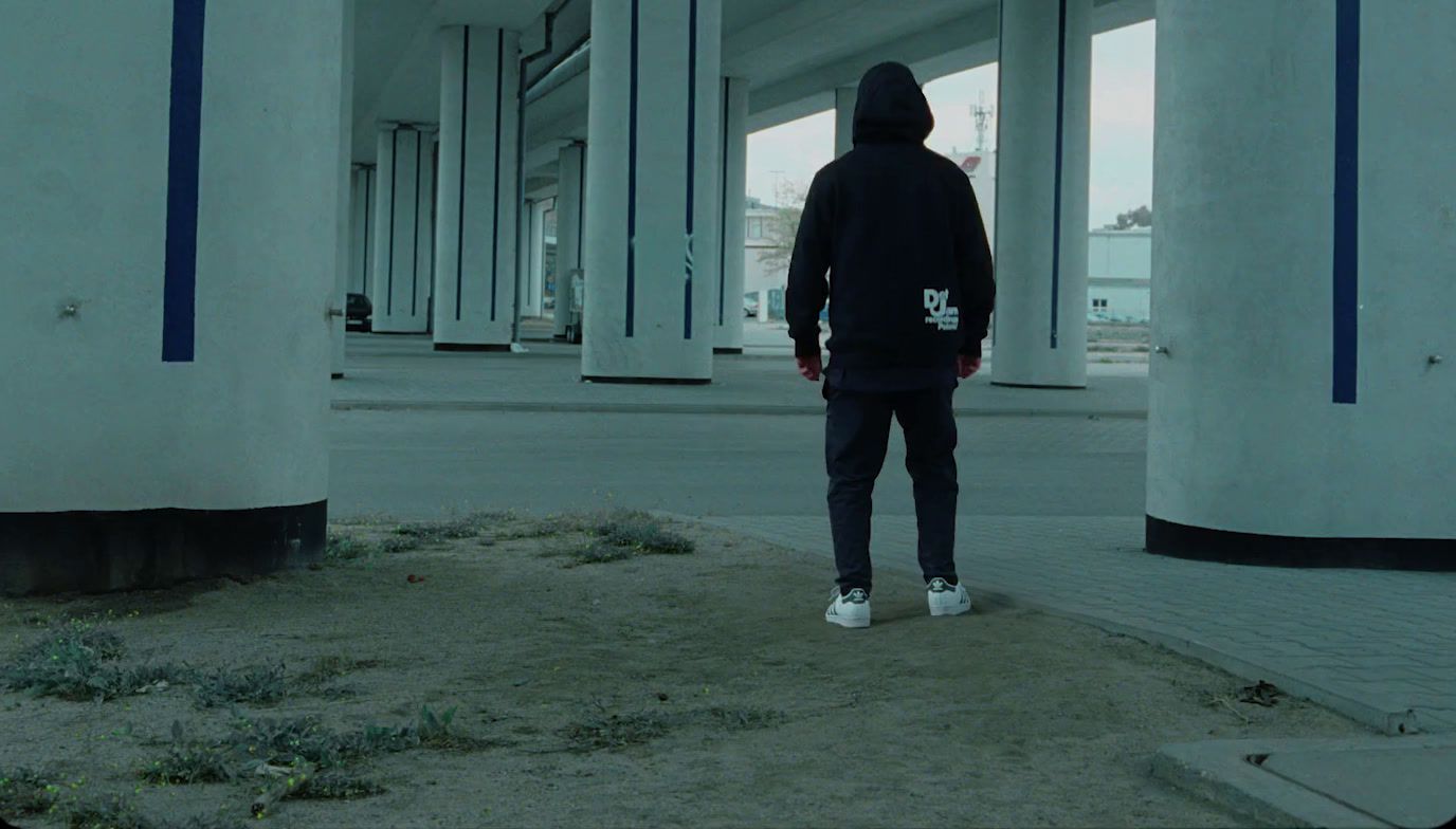 a man in a black hoodie standing in a parking lot