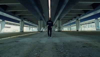 a man in a black shirt is standing under a bridge