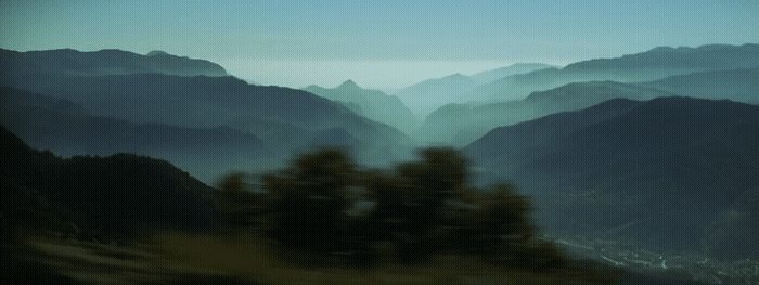 a blurry photo of a mountain range with trees in the foreground