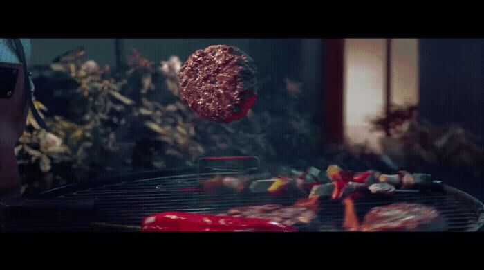 a hamburger being cooked on a grill with ketchup