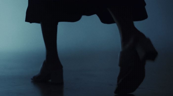 a woman's legs and shoes in a dark room