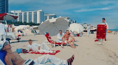 a group of people sitting on top of a sandy beach