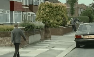 a man walking down a street next to a car