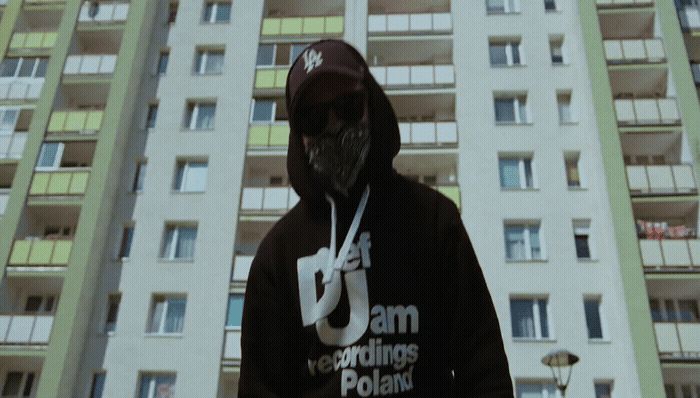 a man in a hoodie standing in front of a tall building