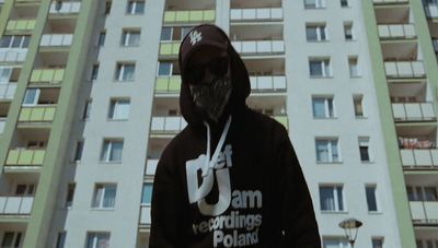 a man in a hoodie standing in front of a tall building