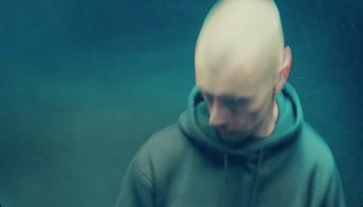 a man with a bald head wearing a green hoodie