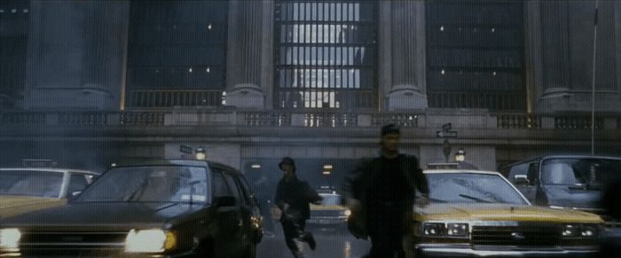 a group of people walking down a street next to parked cars