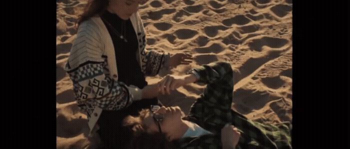 a group of people sitting on top of a sandy beach