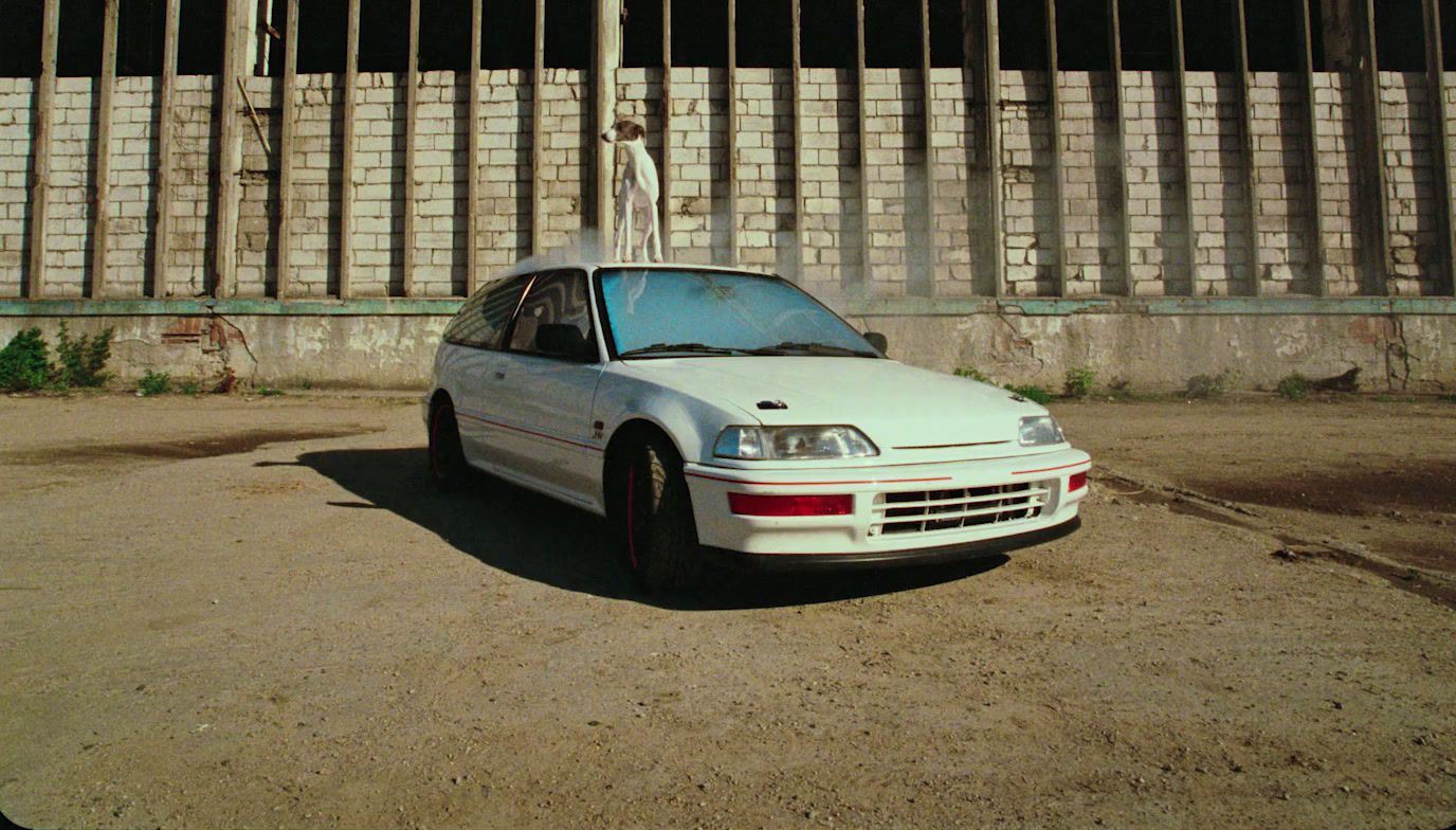 a white car parked in front of a fence