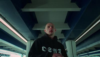 a man standing under a blue and white bridge