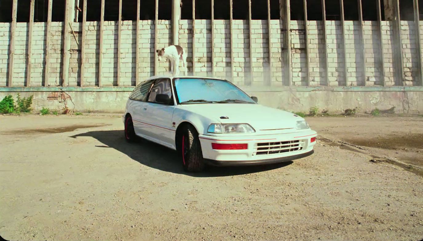 a white car parked in front of a fence