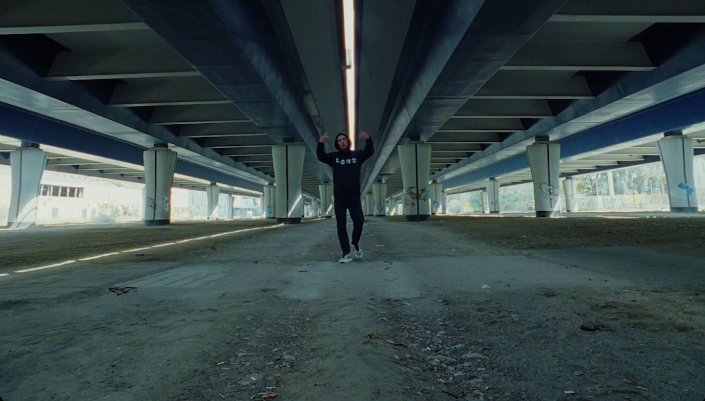 a man in a black wet suit standing under a bridge