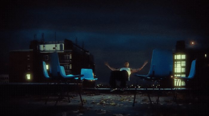 a man standing in front of two blue chairs