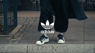 a person wearing adidas shoes standing on a sidewalk