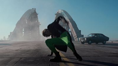 a man in a black jacket and green pants on a runway