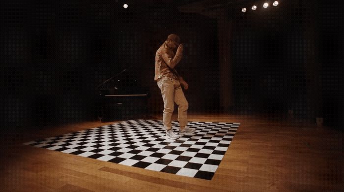 a man standing on a checkered floor in front of a piano