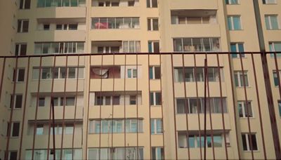 a tall building with lots of windows next to a fence