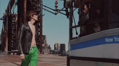 a man in green pants standing next to a bus