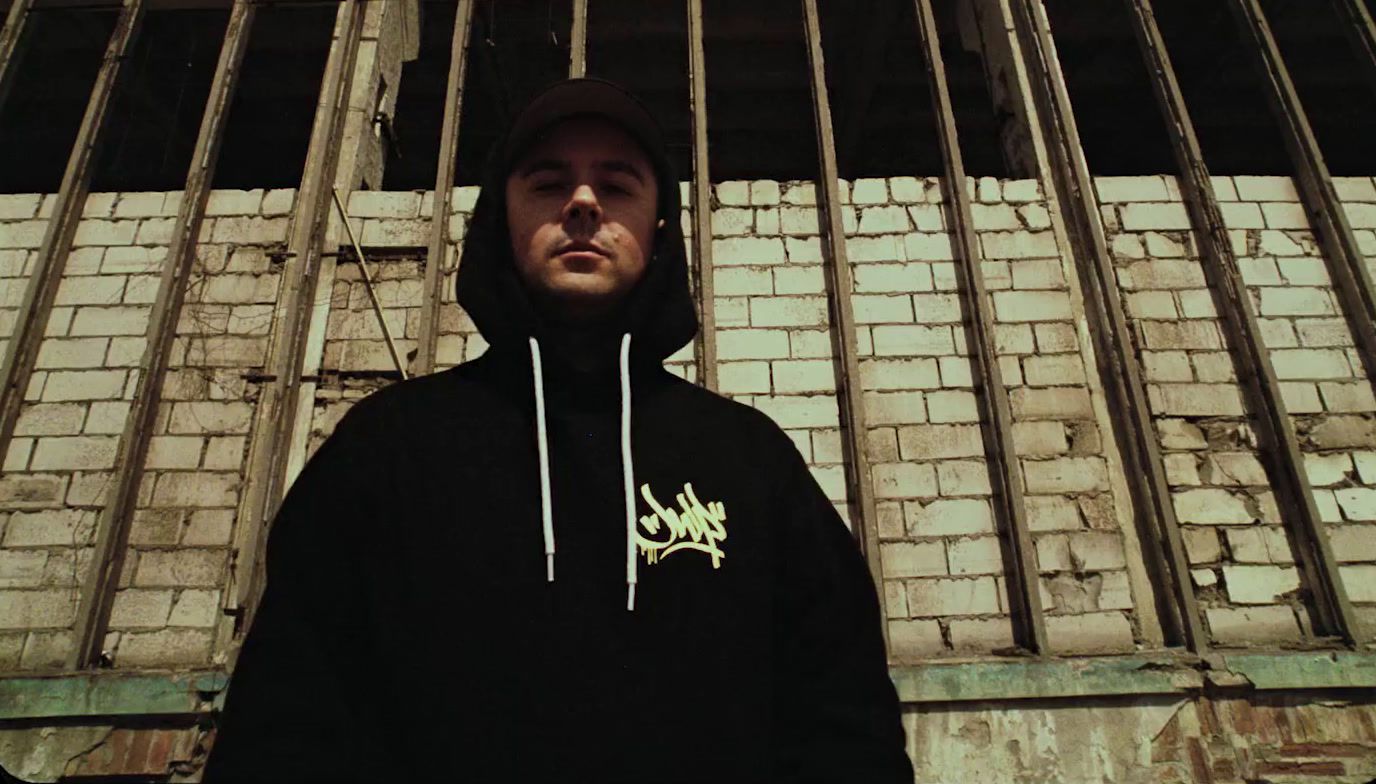 a man standing in front of a brick wall