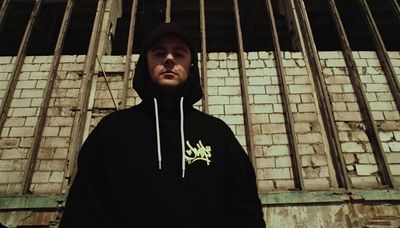 a man standing in front of a brick wall