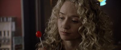 a woman with curly hair holding a lollipop