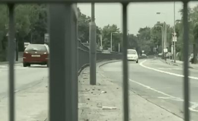 a car driving down a street next to a fence