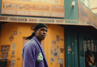 a man in a purple jacket standing in front of a building