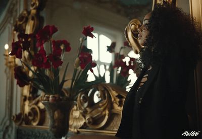 a woman standing in front of a mirror next to a vase of flowers