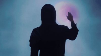 a silhouette of a person with their hands up in the air