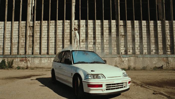 a white car parked in front of a fence