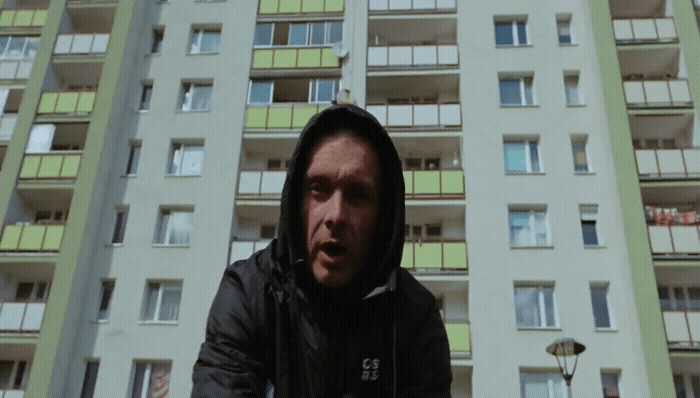 a man in a hoodie standing in front of a tall building