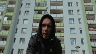 a man in a hoodie standing in front of a tall building