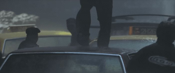 a man standing on top of a car in the rain