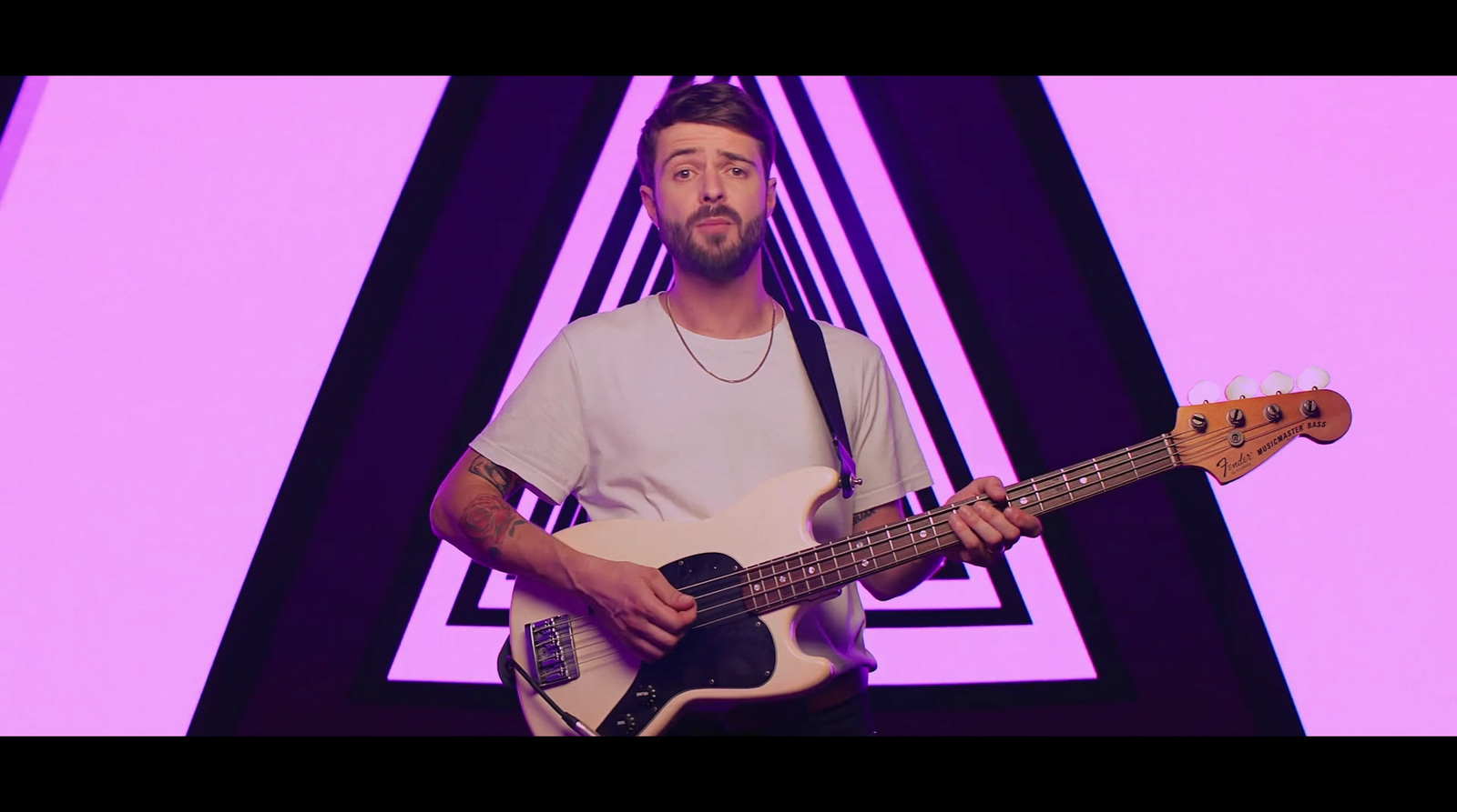 a man holding a bass guitar in front of a purple background