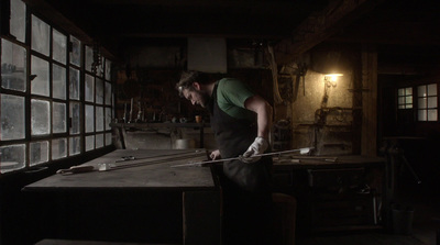 a man working on a piece of wood in a dark room