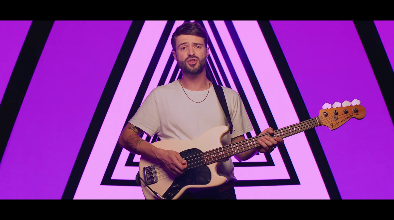 a man holding a bass guitar in front of a purple background