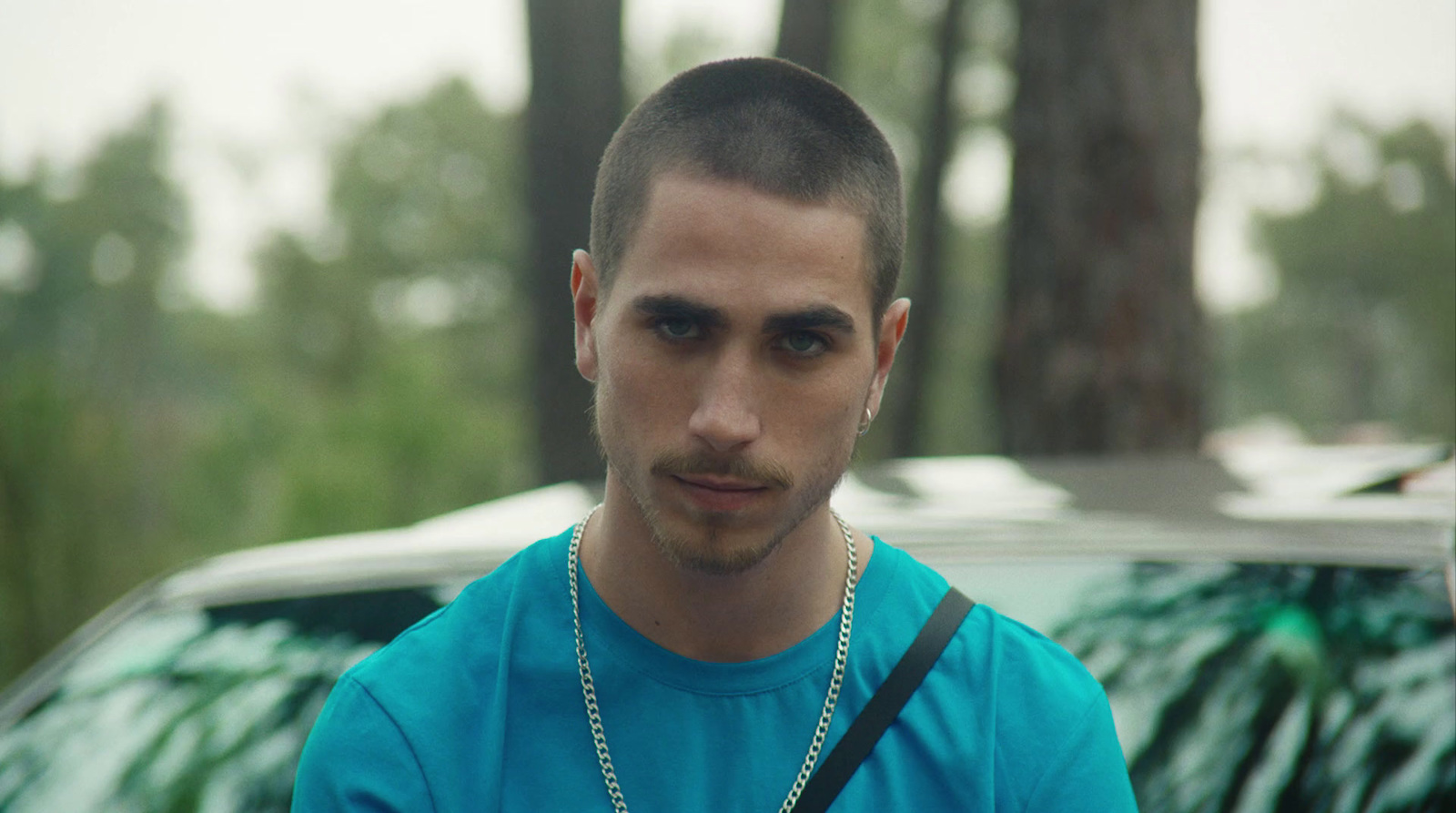 a man in a blue shirt standing in front of a car