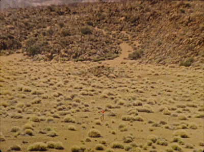 a field with a dirt hill in the background