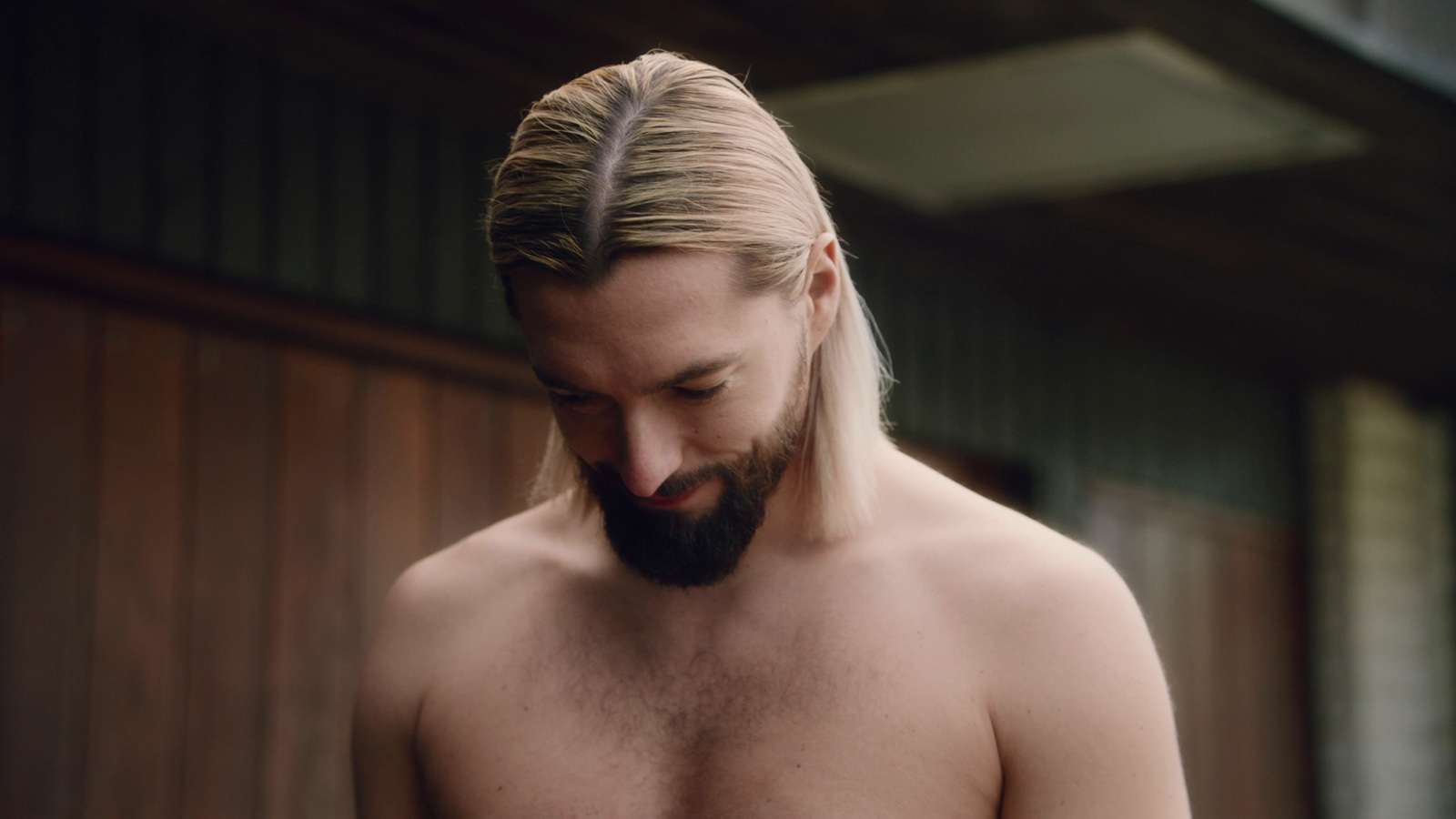 a man with long hair and a beard is looking down