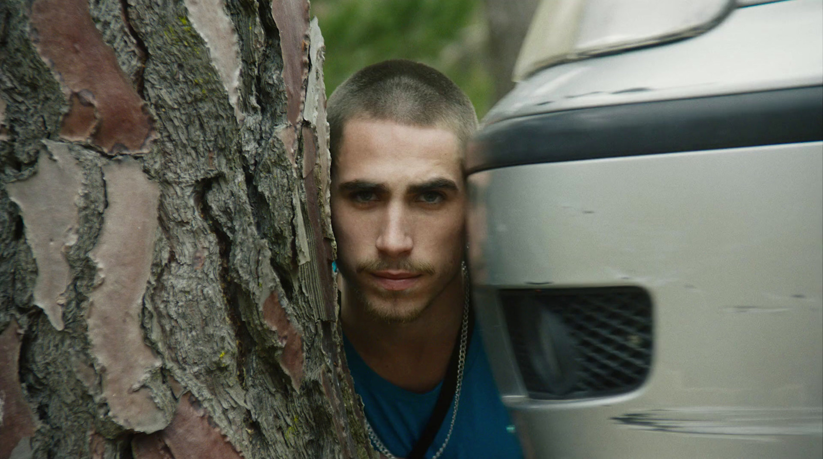 a man peeking out from behind a tree