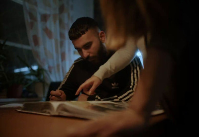 a man sitting at a table writing on a piece of paper