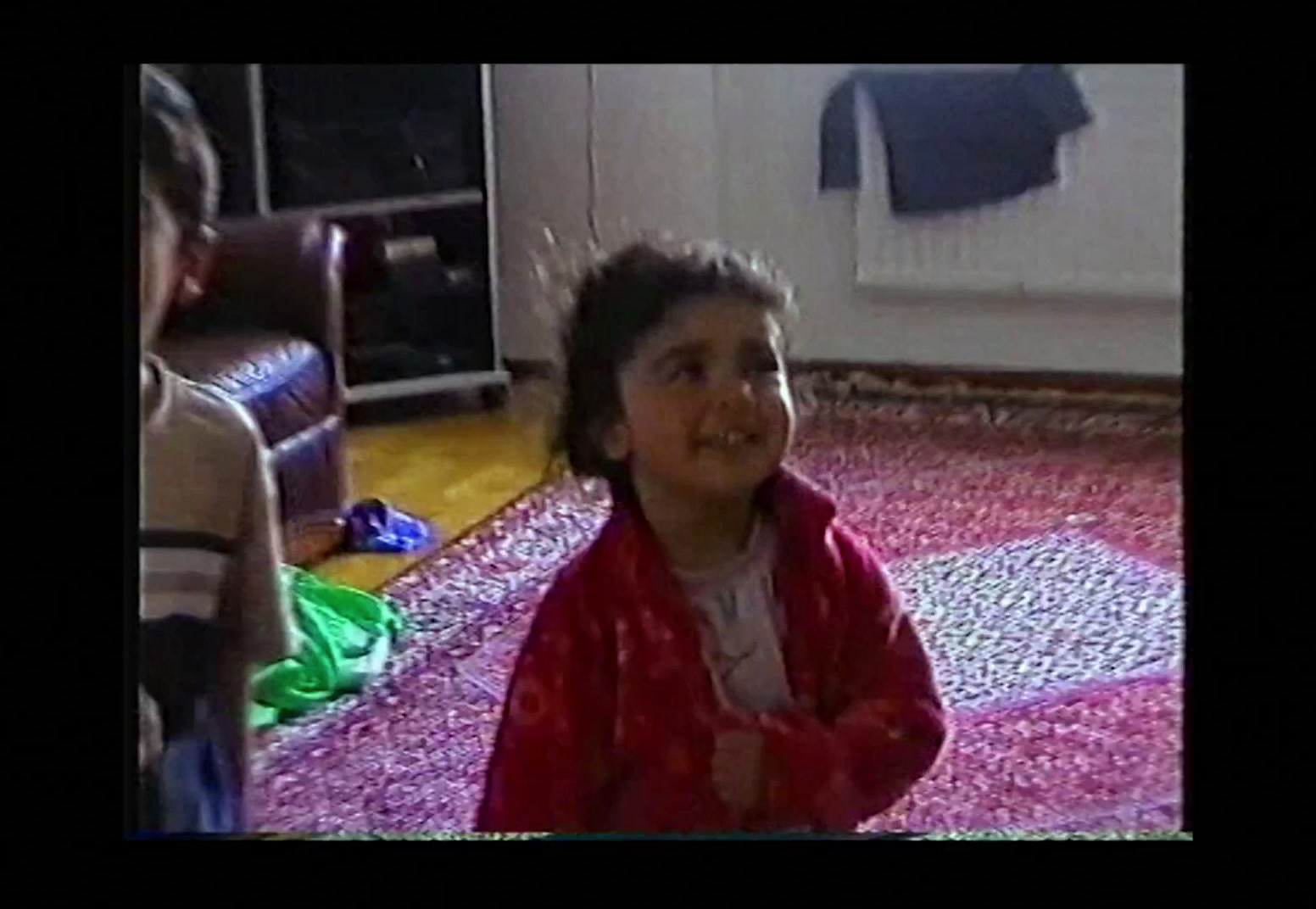 a little girl sitting on the floor in a living room